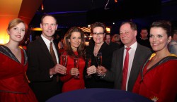 Bildunterzeile: Stoßen auf ein erfolgreiches Grand Opening an: Spielbankdirektorin Claudia Bieling (3.v.r.), Peter Laschkowsky (Leiter Klassisches Spiel, 2.v.l.), Moderatorin Katrin Huß (3.v.l.) Reinhard Wehner (Leiter Automatenspiel, 2.v.r.), umringt von zwei „Roulettas“