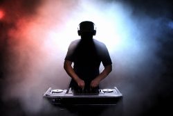 Disc jokey, DJ, silhouette over foggy illuminated background