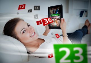 Frau mit Tablet beim Online Casino Spielen auf der Couch
