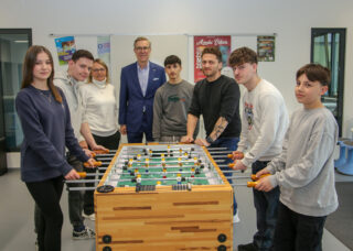 Freudige Gesichter bei der Übergabe: Lucy-Marie (v.l.n.r.), Panos, Rektorin Gisela Bednar, Mario Hoffmeister, Ahmed, Schulsozialarbeiter Alexander Stephan, Noori und Robin freuen sich über das neue Spielgerät. (Foto: Merkur Group)