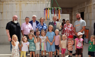 Großer Moment: Kita-Leiter Christian Albrecht (hinten von links), Ortsvorsteher Max Grote, Frank Kögel, Susanne Sassenberg, Paul Gauselmann, Karin Gauselmann und Manuel Wiens freuen sich mit den Kindern über den Baufortschritt. (Foto: Merkur Group)