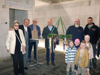 Feierlicher Moment: Karin und Paul Gauselmann (von links), Frank Kögel, Dr. Henning Vieker, Kita-Leiter Christian Albrecht, Manuel Wiens sowie einige Kita-Kinder freuen sich, dass der Richtkranz nun angebracht wird. (Foto: Merkur Group)