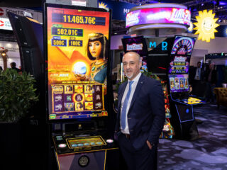 The Multigamer Mod Ex impresses with its unique modularity. Here: Athanasios ‘Sakis’ Isaakidis, Chief Executive International at Merkur Gaming, next to the J-Curved version at ICE 2024. (Photo: Merkur Group)