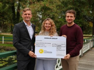 Freuen sich über 1.640 Euro für den guten Zweck: Lena Herms (Mitte), Chefin vom Dienst bei Radio Westfalica, und Christopher „Chrissi“ Menzel (rechts), Moderator von „doppelt wach“, nehmen den Scheck aus den Händen von Björn Bünermann entgegen. (Foto: Merkur Group)